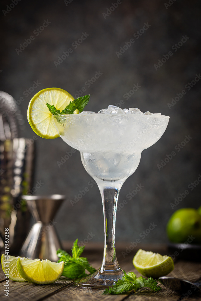 Cocktail margarita garnished with lime and mint on wooden background