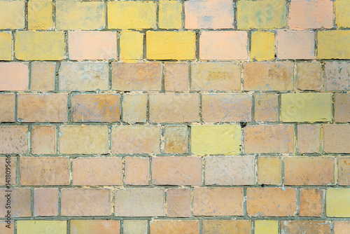A wall made of yellow and pink bricks. The bricks are stacked in a pattern.