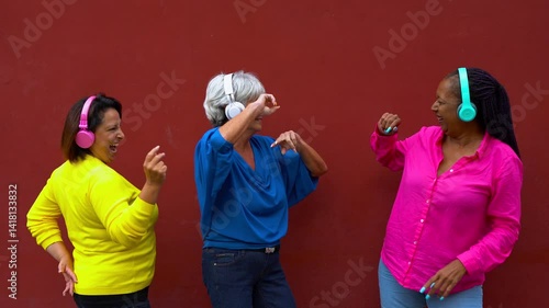 Multiracial senior women having fun dancing together to music playlist in the city - Joyful elderly friendship and technology concept