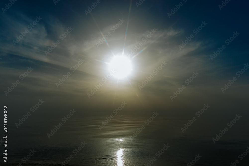 Fototapeta premium Tranquil sunset over a smooth beach shoreline with gentle waves and golden reflections on wet sand. Warm light fills the sky and water, creating a peaceful mood.