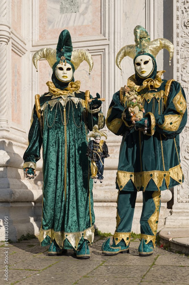 Obraz premium Venice, Italy - People dressed in carnival masks are photographed by tourists in the scenery of the ancient Venetian palaces