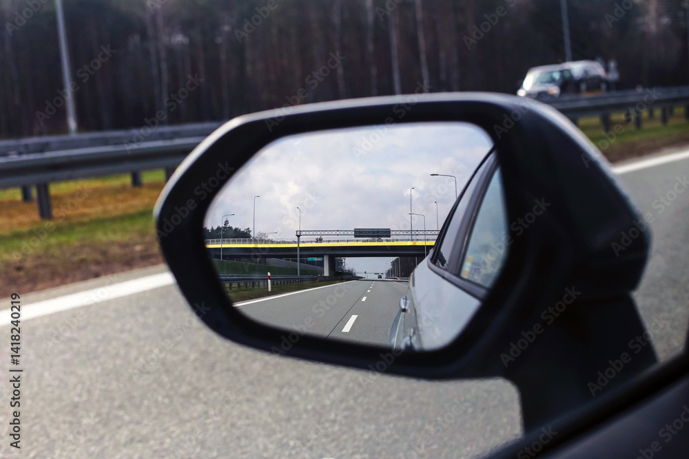Highway in car mirror. Rearview road reflection. Fast travel concept. Modern asphalt route. Vehicle on motorway. Driving on freeway. Motion and journey. Urban traffic infrastructure. Highway in car mirror. Rearview road reflection. Fast travel concept. Modern asphalt route. Vehicle on motorway. Driving on freeway. Motion and journey. Urban traffic infrastructure.