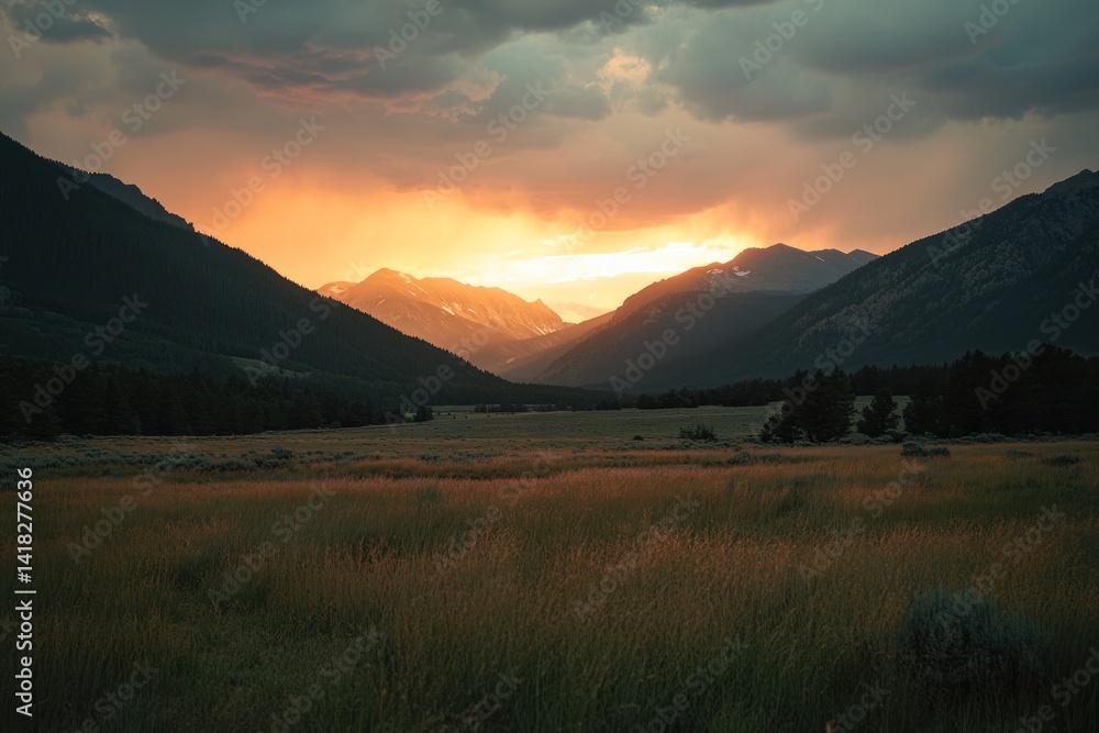 Obraz premium Mountain valley with meadow at sunset; dramatic sky with orange and grey clouds.
