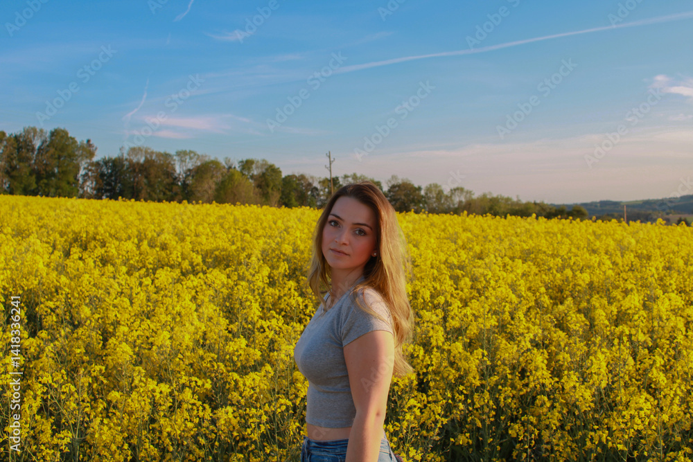 Young woman standing in blooming rapeseed field during golden hour – peaceful spring countryside scene with scenic landscape and natural beauty Young woman standing in blooming rapeseed field during golden hour – peaceful spring countryside scene with scenic landscape and natural beauty