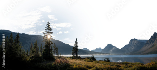 Photography Panorama of calm lake, mountains and trees looking at the sun with a partially t