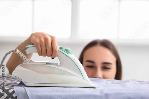 Obraz na płótnie Pretty young woman ironing clothes at home, closeup w salonie