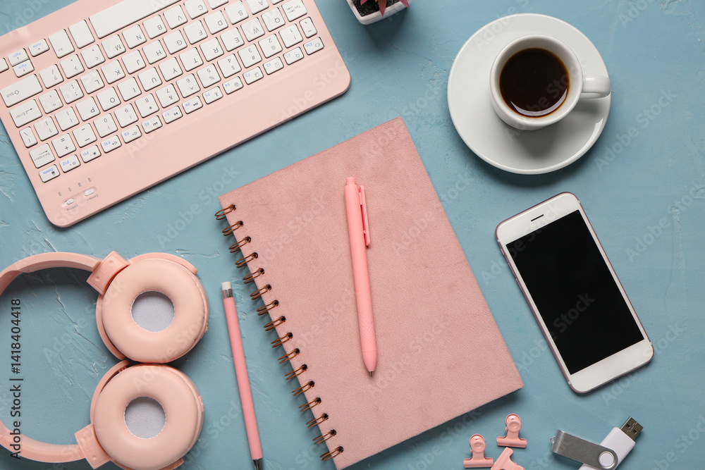 Notebook, cup of coffee, computer keyboard and headphones on blue background