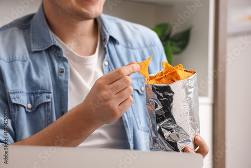Young man eating tasty nach...