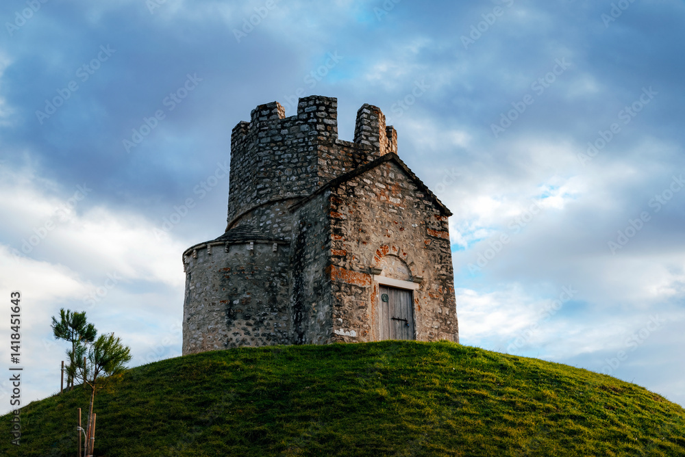 Old stone church on a grassy hill against a cloudy sky. Church of St. Nicholas, Sveti Nikola, Nin town, Croatia Old stone church on a grassy hill against a cloudy sky. Church of St. Nicholas, Sveti Nikola, Nin town, Croatia