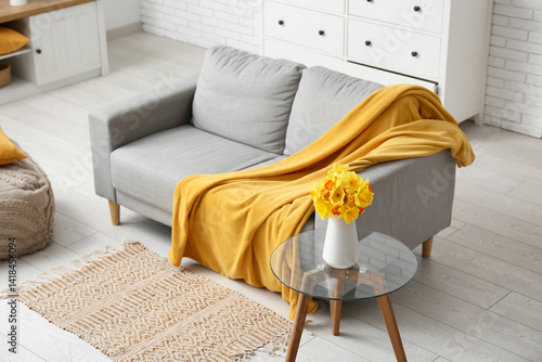 Obraz na płótnie Cozy sofa with coffee table and narcissus flowers in living room w salonie