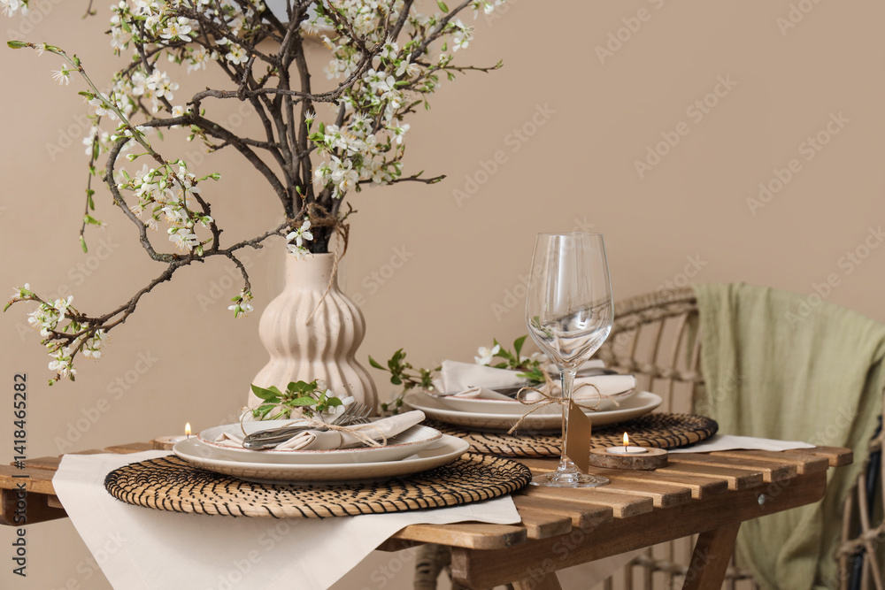 Elegant table setting with plates, burning candle and blooming tree branches