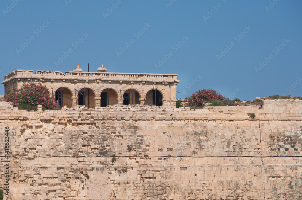 Fototapeta premium A building with a balcony and a wall of stone