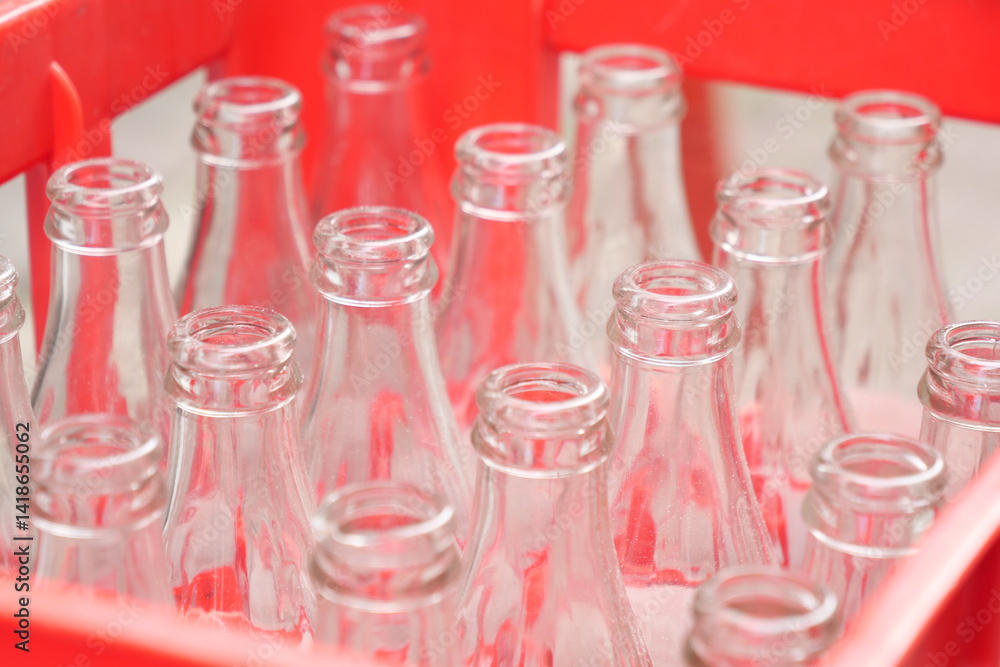 Glass bottles neatly arranged in a red crate at a market Glass bottles neatly arranged in a red crate at a market