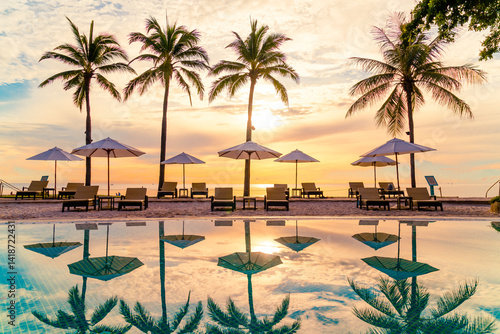 Umbrella and chair around swimming pool in resort hotel for leisure travel and vacation neary sea ocean beach