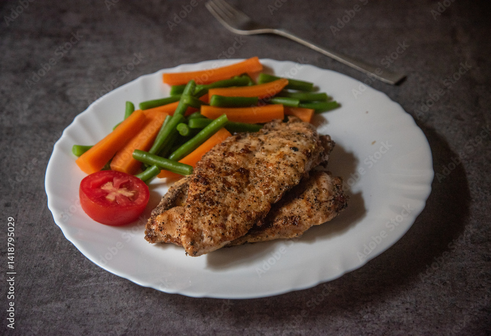 Grilled chicken steak with vegetables on a plate. Close up, selective focus.