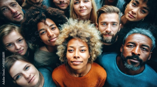A close-up shot of a diverse group of people looking up towards the viewer with a smile.