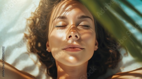 Obraz na płótnie A woman's face with closed eyes enjoys the warmth of the sun, shaded by a palm leaf. w salonie