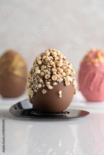 Close up of milk chocolate egg decorated with crushed crispy pearls. Easter mousse desserts and treats.
