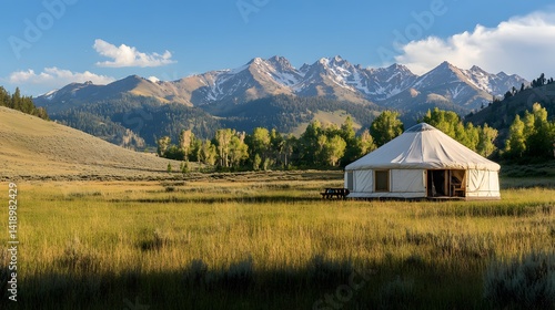 Fototapeta Naklejka Na Ścianę i Meble -  A yurt set up on a grassy plain with mountains in the background