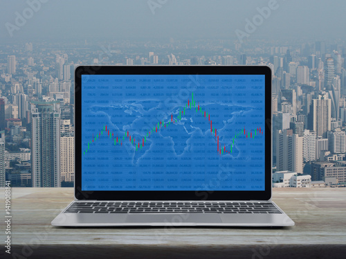 Fototapeta Naklejka Na Ścianę i Meble -  Trading graph of stock market with world map and graph on laptop computer on wooden table over city tower and skyscraper, Business investment online concept, Elements of this image furnished by NASA