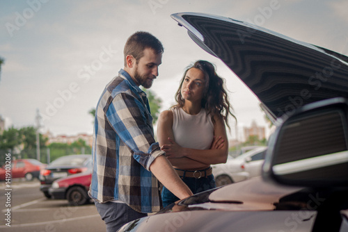 Young couple on the road having problem with a car. Open hood of broken car. Car service, transportation concept