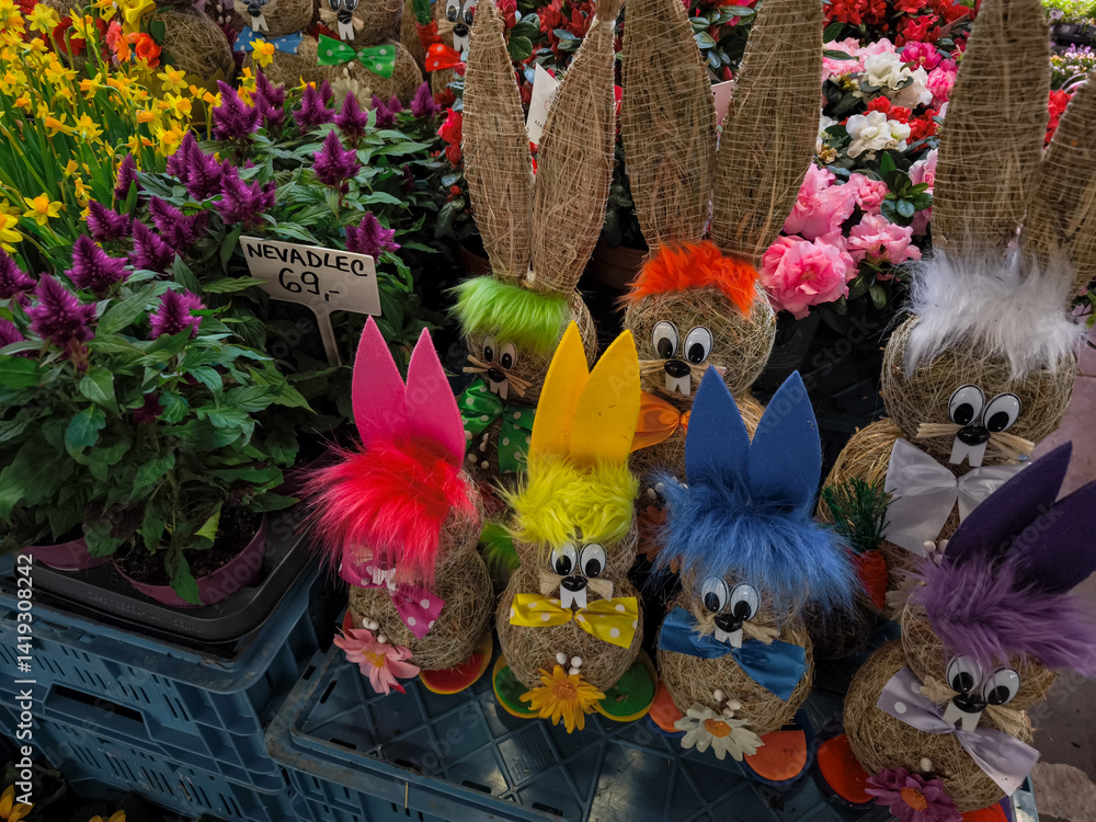 Colorful easter bunnies sitting next to flowers at market stall in Prague Holesovice, Czech republic