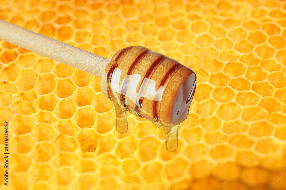 Honey dripping from dipper near filled honeycomb, closeup Honey dripping from dipper near filled honeycomb, closeup