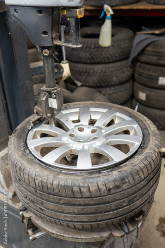 Принти на полотні Tire mounting machine securing a summer tire onto a silver multi-spoke alloy wheel in a service garage