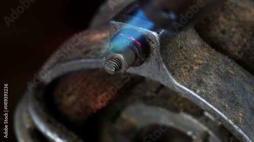 Mechanic heating up the stucked rusty nut bolt with a gas torch blower.