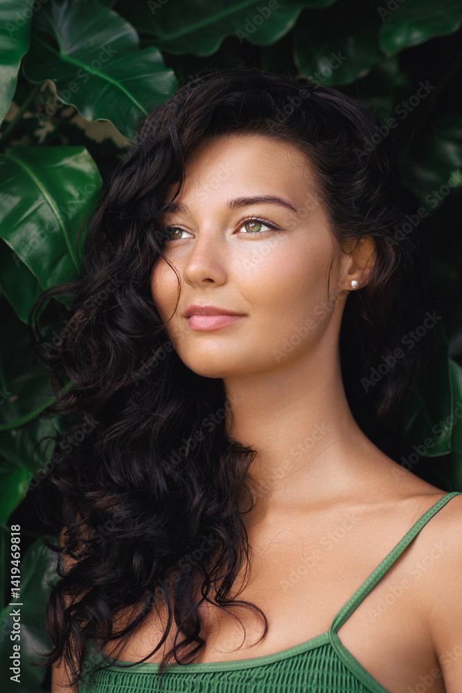 Elegant woman with captivating green eyes and curly hair posing gracefully against vibrant tropical leaves. Ideal for beauty, summer fashion, nature-inspired photography, and luxury lifestyle Elegant woman with captivating green eyes and curly hair posing gracefully against vibrant tropical leaves. Ideal for beauty, summer fashion, nature-inspired photography, and luxury lifestyle