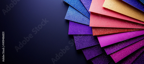 Vibrant glitter paper in various colors arranged in fan shape, showcasing shades of purple, pink, red, and gold against dark background, creating visually striking and artistic display