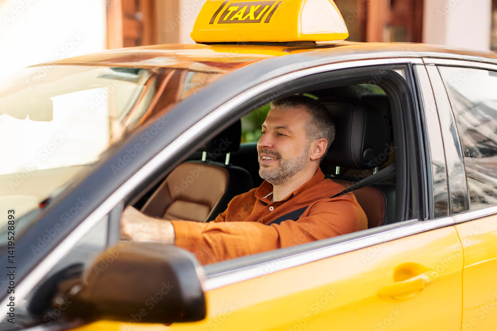 Naklejka premium Photo of middle aged driver man sitting in yellow taxi, driving on city street with smile, holding hands on steering wheel