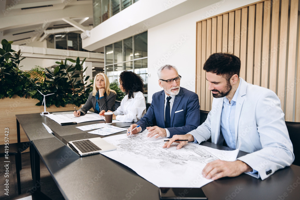 Architects and engineers studying blueprint for wind farm project Architects and engineers studying blueprint for wind farm project