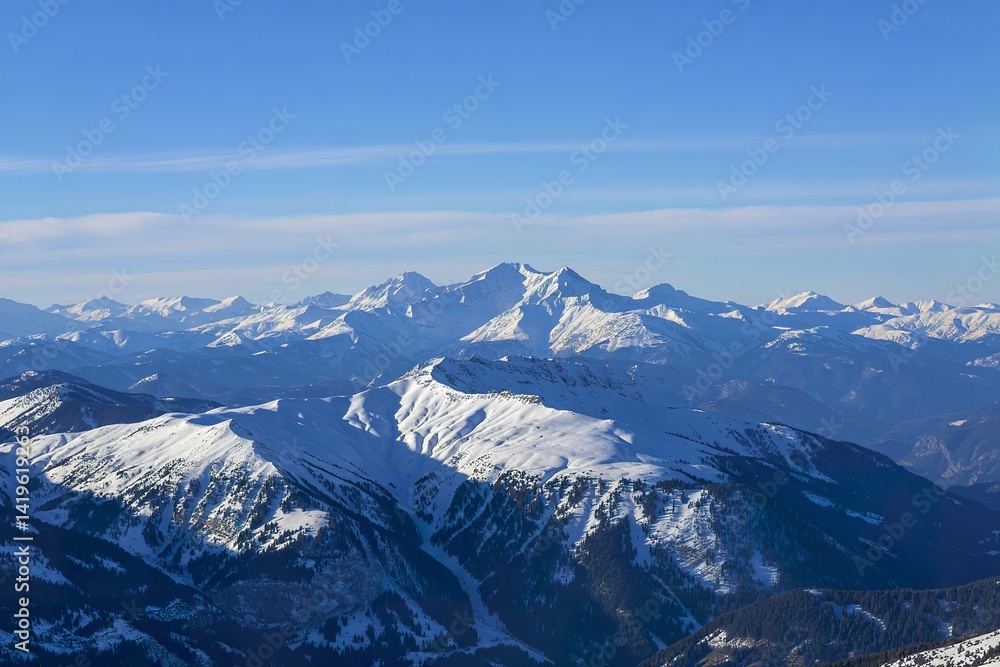 A panoramic photograph of snow-covered mountain ranges under a clear blue sky. A panoramic photograph of snow-covered mountain ranges under a clear blue sky.