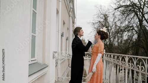 Nobleperson pair sharing tender moment on ornate balcony, wearing intricate 19th-century attire, exuding romantic elegance against architectural backdrop
