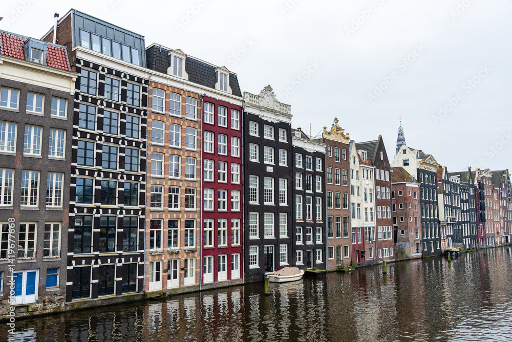 Traditional colorful dutch houses reflecting on amsterdam canal under cloudy sky. House apartments