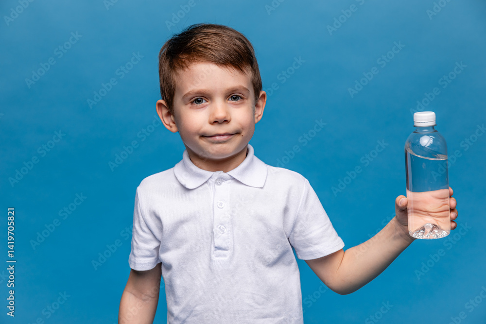 A happy little boy drinks water for health on a blue background. The child is holding a water bottle. A kid with a plastic bottle. Children's activity and energy, generation Z. body hydration concept