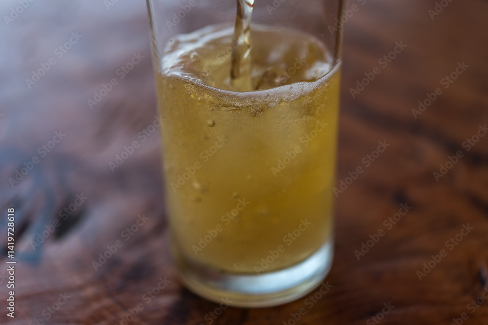 Pouring beer water in to glass with ice and froth Pouring beer water in to glass with ice and froth