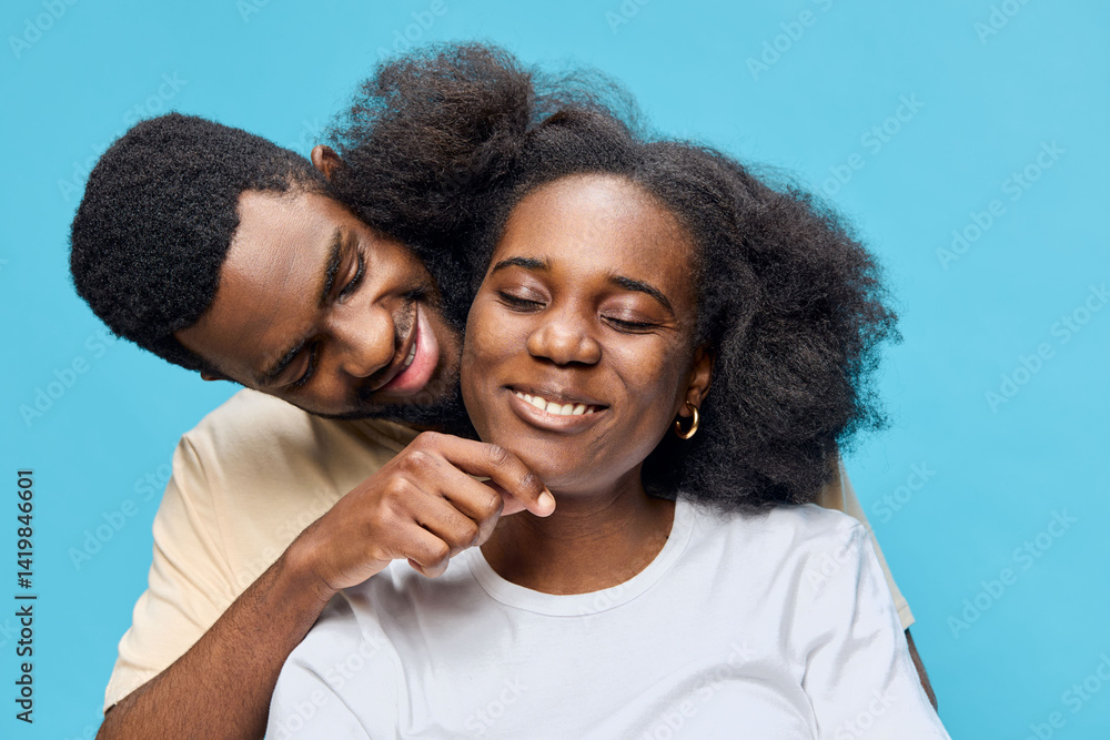 Happy couple embracing with joyful expressions, showcasing love and connection against a bright blue background, emphasizing their warmth and affection