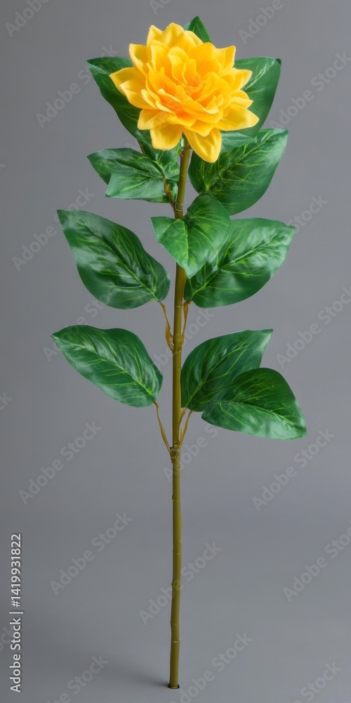 Single artificial yellow dahlia flower with green leaves on a gray background. Single artificial yellow dahlia flower with green leaves on a gray background.