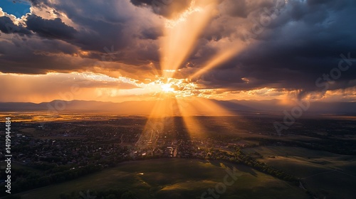 Golden hour light streams through dramatic clouds over a landscape and a town