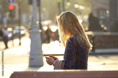 Obraz na płótnie Girl with long blonde hair using smartphone on city street in sunlight w salonie