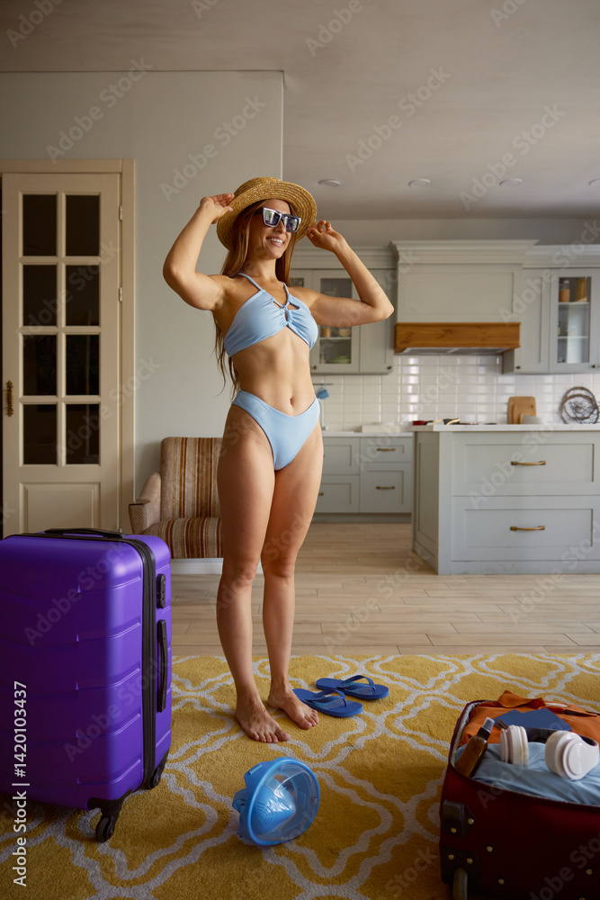 Dreamy woman tourist wearing swimwear standing at travel suitcases