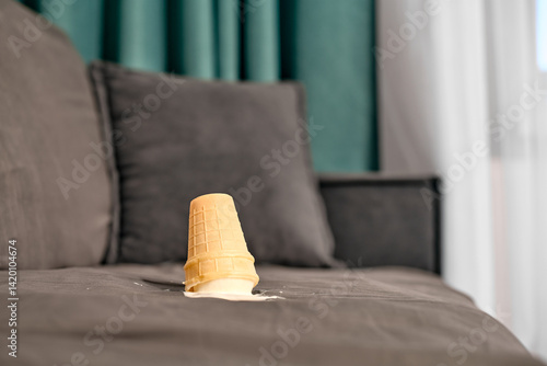 Vászonkép Vanilla ice cream cone lies upside down on grey sofa