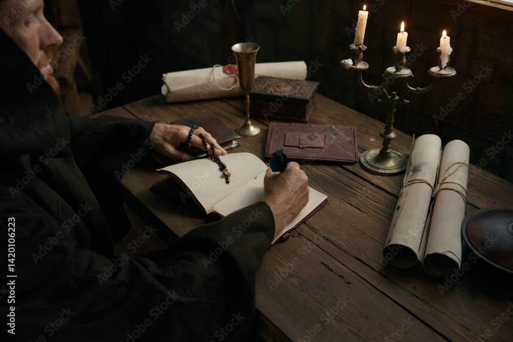 Crop shot of medieval monk chronicler writing ancient manuscript under candlelight
