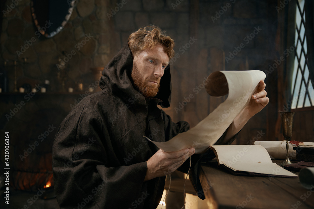 Medieval monk wearing robe with hood reading sacred manuscript on parchment