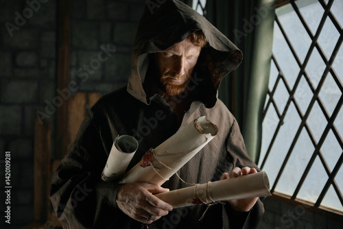 Obraz na płótnie Medieval monk holding obsolete historical parchments and holy manuscripts w salonie