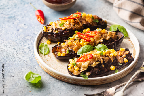 Baked aubergines boats, stuffed with minced meat, tomatoes, corn, garlic and cheese in white plate