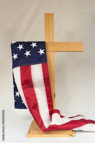 Vászonkép An American flag draped gracefully over a wooden cross on a white background, representing faith, freedom, patriotism, and Christian Nationalism