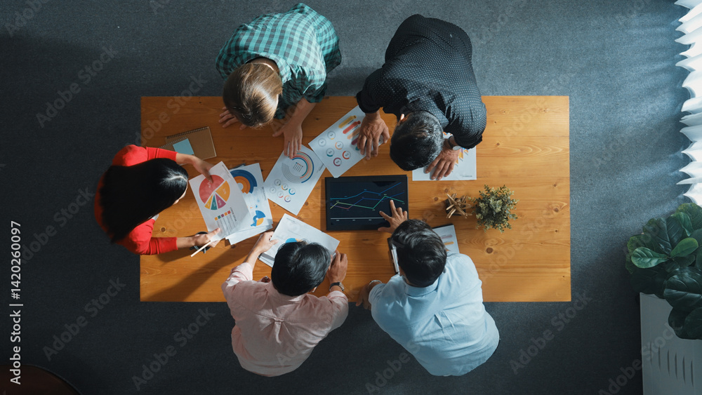 Top down aerial view of smart business people analyze data together at meeting. Group of business team working together and looking at financial chart at tablet placed on meeting table. Convocation.